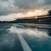 Pit lane inondée d'un circuit tropical sous la pluie, tribune vide au fond