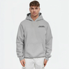 Homme portant un hoodie gris clair TOURISMO avec pantalon blanc, sur fond blanc