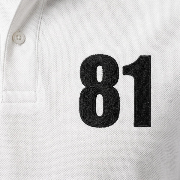 Gros plan sur le 81 brodé en noir du polo blanc Oscar Piastri