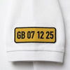 Gros plan sur la plaque GB 07 12 25 brodée sur la manche du polo blanc