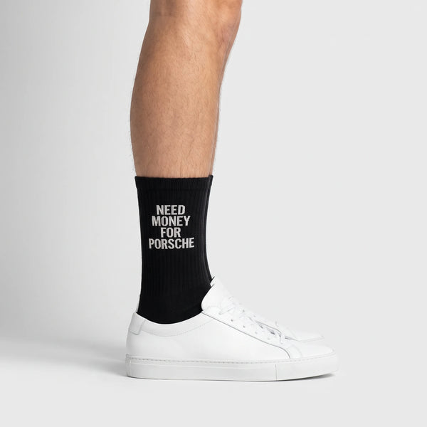 Calzini Need Money For Porsche nero, indossati, vista laterale con sneakers bianche